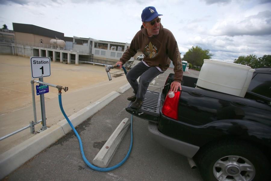 Leon Jung hops off the tailgate of his truck after filling two 55-gallon barrels with recycled water at the Dublin San Ramon Services District on April 6, 2015, in Pleasanton, Calif. Jung uses the recycled water for his lawn, garden, and flowers. (Aric Crabb/Bay Area News Group/TNS)